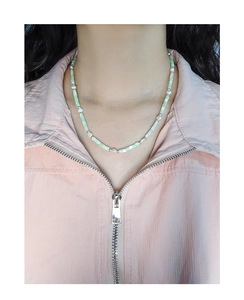 Detailed view of Baroque pearl and green shell beaded necklace worn on a female neck