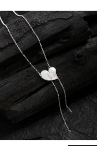 Detail of silver S925 heart pendant with butterfly motif on black wood background