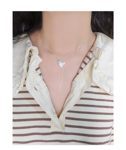 Close-up of S925 sterling silver heart tassel necklace on a striped shirt