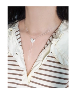 Detailed view of S925 silver heart tassel necklace worn by a model on a beige shirt