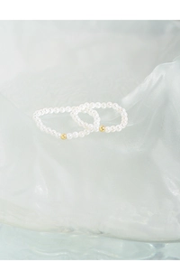 Detailed close-up of 2mm minimalist pearl rings with gold accents on icy background