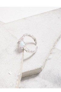 Detail of molten lava textured silver ring with heart-shaped opal stone on stone background