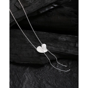 Minimalist S925 sterling silver heart tassel necklace with layered bow design on black background