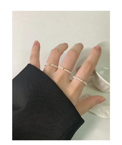Detailed view of three 2mm pearl bead rings with gold accent beads worn on fingers