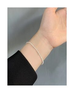 Detail of minimalist S925 silver pearl bracelet with small white round beads on wrist