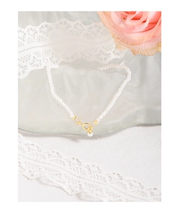 Detailed close-up of elegant pearl bracelet with gold clasp on frosted glass and lace