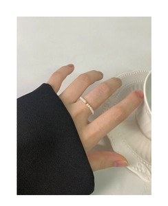 Detail of 2mm minimalist pearl ring with a single gold bead on woman's finger