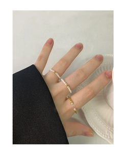 Detail of stacked 2mm pearl rings and gold twisted rope ring on model hand