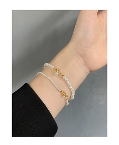 Close-up of double-layer pearl bracelet with gold hardware worn on female model wrist