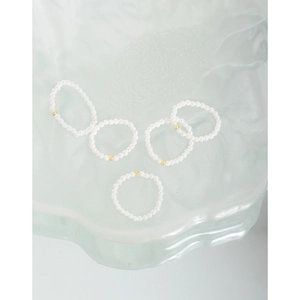 Minimalist S925 sterling silver 2mm pearl rings with gold beads on ice glass surface