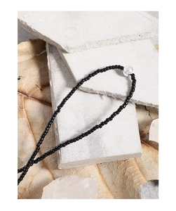Artistic detail of S925 silver necklace with black agate beads on stone and dried leaves