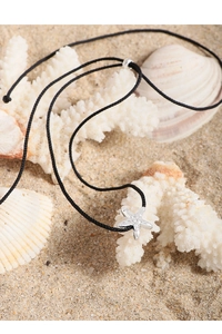 Close-up of a silver starfish pendant with textured finish on a black cord necklace