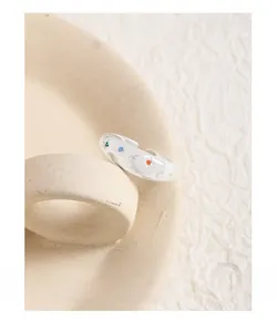 Macro shot of silver crescent moon and star ring with colorful zircon inlays on ceramic