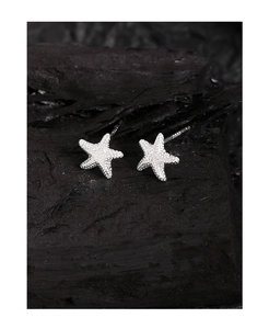 Dettaglio ravvicinato di orecchini a stella marina in argento S925 con texture fine
