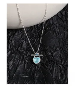 Detail of silver S925 necklace featuring a light blue heart pendant and OT toggle clasp