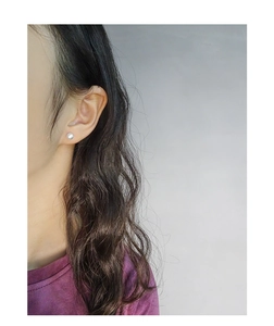Close-up of minimalist white pearl stud earring worn on the earlobe for a classic look