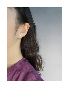 Close-up of minimalist matte round ball stud earring worn on a model's ear
