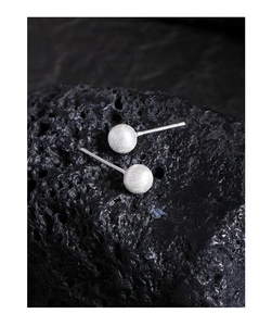 Detail of matte brushed silver ball stud earrings on a black lava stone background