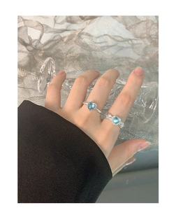 Macro detail of S925 silver rings with heart-cut blue gemstones on a model's hand