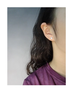 Close-up of a model wearing minimalist matte white pearl stud earrings in S925 silver