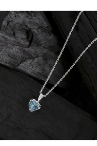Détail macro du collier cœur en argent S925 avec pierre bleue sur fond texturé