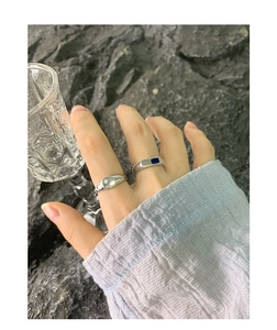 Close-up of S925 silver rings with star engraving and blue stone on textured stone