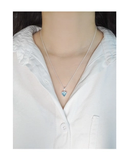 Gros plan d'un collier avec pendentif cœur bleu clair porté par un mannequin