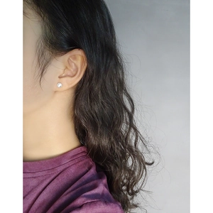 Minimalist matte round stud earrings in S925 sterling silver worn by a model