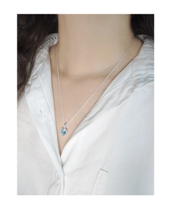 Gros plan du collier en argent S925 avec pendentif cœur bleu clair porté par un mannequin