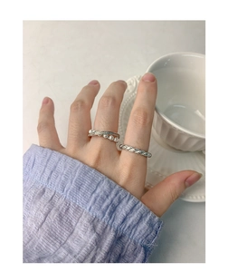 Macro view of silver wave ring with pearls and pavé stones layered on a finger