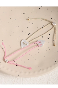 Macro view of S925 silver heart pendants on braided cords in pink and green colors
