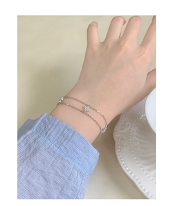 Bracelet double rang en argent avec trèfles en zircone porté au poignet