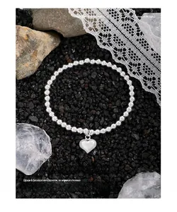 Détail d'un bracelet en perles d'argent S925 avec pendentif cœur sur pierres sombres