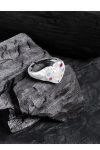 Macro detail of silver heart ring featuring vibrant colorful cubic zirconia and fluid patterns