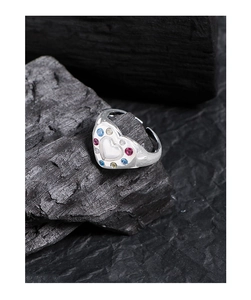 Detailed macro of a S925 silver heart ring with colorful zircons on a dark coal background