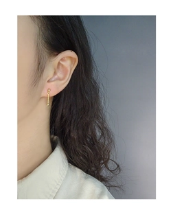 Detailed close-up of a minimalist gold chain earring featuring a simple ball stud design