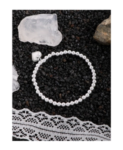 Détail du bracelet en perles d'argent S925 avec pendentif cœur sur fond de pierre noire
