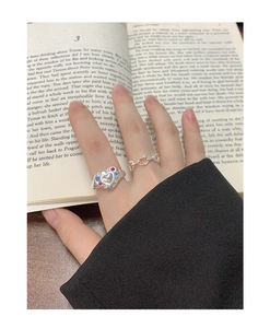 Close-up of S925 silver heart ring set with colorful zircon stones on an open book