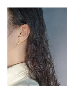 Close-up of a gold shell-shaped earring with elegant wavy texture on a female model