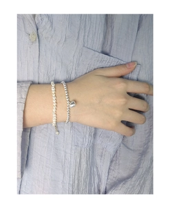 Détail d'un bracelet multicouche en argent S925 avec cœur et perles blanches au poignet