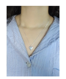 Close-up of heart-shaped 925 silver necklace with blue gemstone on model's neck
