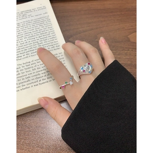 Retro S925 silver ring set with colorful zircons worn over a vintage book background