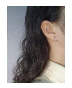 Close-up of a silver shell cross stud earring on ear for minimalist luxury style