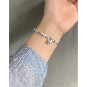 Bracelet minimaliste en argent S925 avec pendentif cœur sur le poignet d'une femme