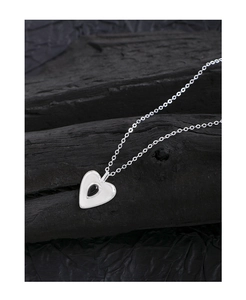 Macro view of silver heart pendant with black drop inlay and delicate chain detail