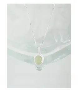 Detailed view of S925 silver necklace with oval green crystal on a crystal ice prop