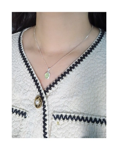Detail of s925 silver necklace featuring a green oval crystal pendant on a female model