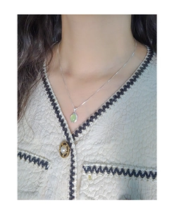 Close-up of S925 silver necklace with oval green crystal on elegant female collarbone