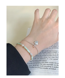 Close-up of silver heart bracelet with pink crystal and light green fluorite beads