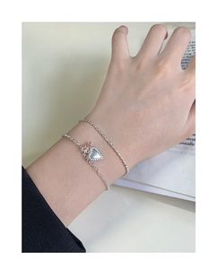 Detail of silver S925 heart pendant bracelet and bead chain worn on a model's wrist